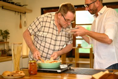 Baba ve oğul ev mutfağında taze ev yapımı yemek yapmayı severler. Babalar Günü konsepti.