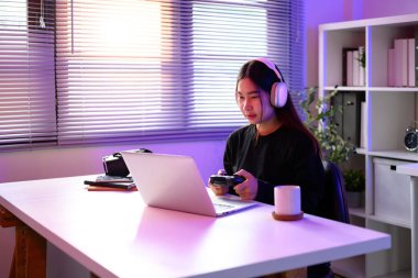 Asyalı bir kadın, neon ışıklı bir masada oyun oynuyor..