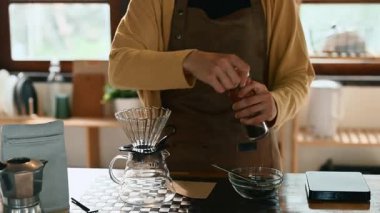 Mutfakta kahve çekirdeklerini öğüten genç bir kadın taze kahve için hazırlanıyor..