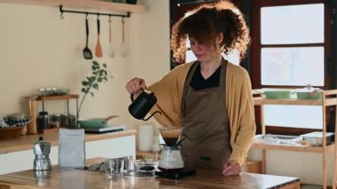 Sakin genç bir kadın metodla taze kahve yapıyor.