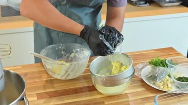 Sıvı tereyağlı sütü ayırmak için tereyağına basılı eldivenlerle ellerini kapat..