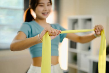 Ev antrenmanı sırasında sarı bir direniş bandını geren formda bir kadına yakın durun..