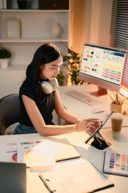 Modern yaratıcı ofiste dijital tablet kullanarak markalaşma projesi üzerinde çalışan tasarımcı kadın..