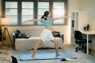 Rahat bir evde yoga yapan bir kadın. Sağlıklı yaşam tarzı alışkanlıkları kavramı.