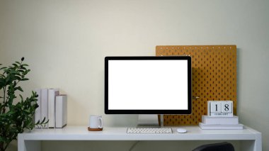 Boş ekran monitörü, bitkisi, tahta duvarı ve takvimi olan çağdaş çalışma istasyonu.