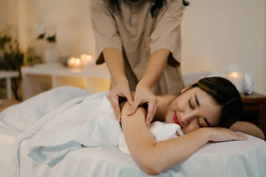 Masaj terapisti masaj yaparken masaj masasında uzanan rahat bir kadın. Refah kavramı.