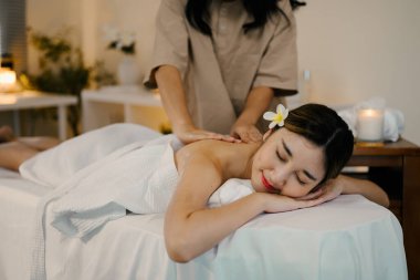 Masaj terapisti masaj yaparken masaj masasında uzanan rahat bir kadın. Refah kavramı.