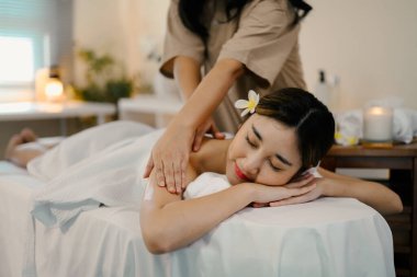 Masaj terapisti masaj yaparken masaj masasında uzanan rahat bir kadın. Refah kavramı.