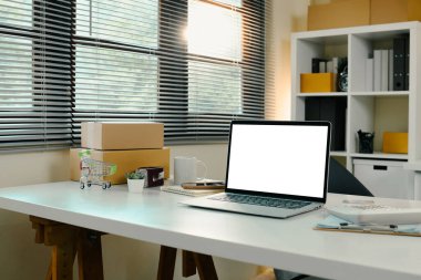 Sevkiyat kutuları, boş ekran dizüstü bilgisayarı ve araçları ile çevrimiçi iş alanı.