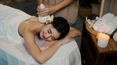 Genç bir kadın lüks bir kaplıcada rahatlatıcı bitkisel masaj yaptırıyor. Refah kavramı.