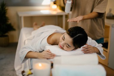 Terapist tedavi için gerekli yağı hazırlarken genç bir kadın masaj masasında dinleniyor..