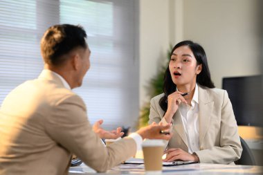 İş arkadaşları dizüstü bilgisayarda birlikte çalışıyor, fikirleri tartışıyor ve proje verilerini bir ofiste gözden geçiriyorlar..