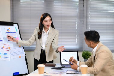 Takım toplantısı sırasında kendine güvenen bir iş kadını beyaz tahtada veri sunuyor..