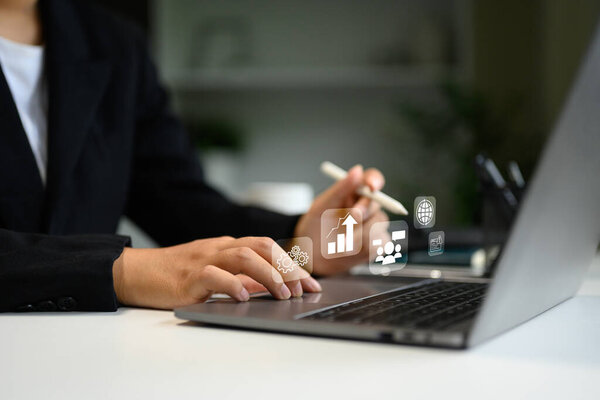Businessperson working on laptop with digital interface icons, symbolizing data analytics, and global connectivity.