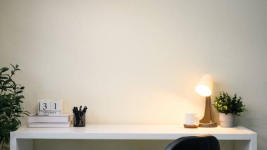 Takvim bloğu, masa lambası ve yeşil bitkisi olan modern minimalist masa.