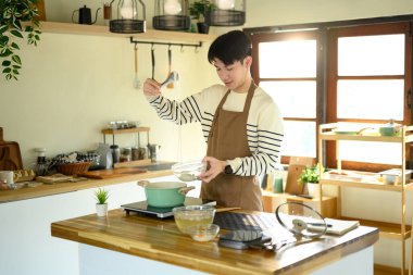 Asyalı adam parlak bir mutfakta erişte tabağı hazırlıyor..