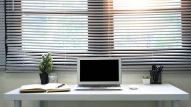 Bilgisayarı, kahve fincanı, not defteri ve kapalı salonda bitkileri olan parlak ofis masası...