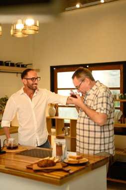 Son sınıf öğrencisiyle oğlu sıcak bir mutfakta kahvelerini yudumluyorlar. Babalar Günü konsepti.