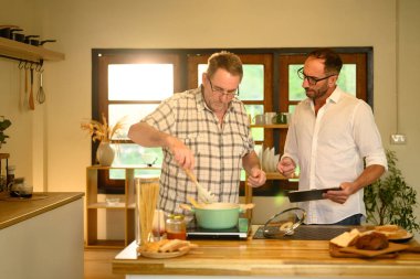 Mutlu kıdemli adam ve oğlu mutfakta ev yemeği hazırlarken eğleniyorlar. Babalar Günü konsepti.