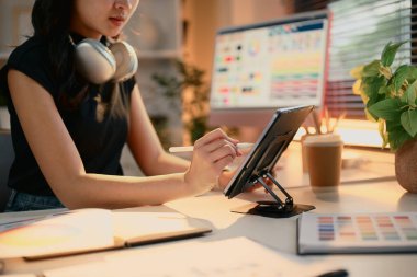 Modern bir masadaki renk örnekleriyle dijital tablet kullanan kadın grafik tasarımcısı.