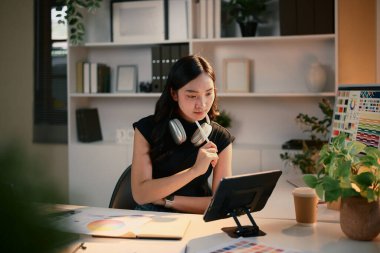 Tasarımcı, şık iş yerinde renk grafikleriyle dijital tablet kullanarak projeye odaklandı.