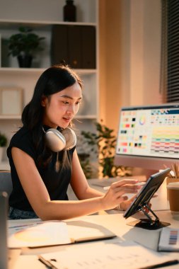 Modern masadaki dijital tablet üzerinde çalışan kadın grafik tasarımcısı. Renk paleti ekranda.