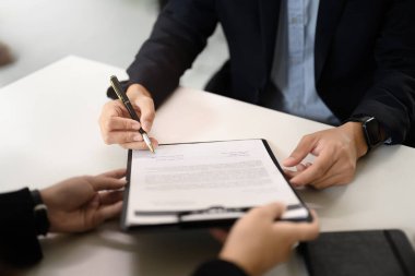 Ofis masasında iki iş adamının incelemesi ve sözleşmeyi imzalaması..