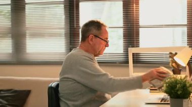 Üst düzey bir adam ofisteki masasını temizliyor, örtüyle yüzeyi siliyor..