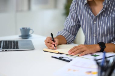 Bir dizüstü bilgisayar ve belgelerle çalışırken iş adamlarının not yazışlarını kapat.