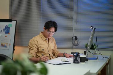 Gece geç saatlerde mali raporları inceleyen ciddi bir ofis çalışanı..