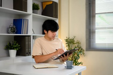 Parlak, düzenli bir ofis masasında çalışan belgelere odaklanmış bir adam..