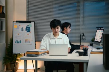 Modern bir ofiste fazla mesai yapan iki genç iş adamı..