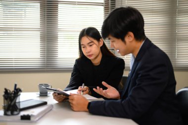 İş adamları resmi bir sözleşme tartışması sırasında evrakları inceliyor ve ayrıntıları görüşüyorlar..