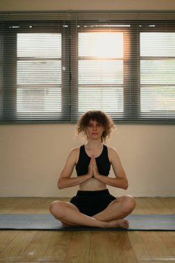 Genç beyaz kadın, huzurlu bir stüdyoda yoga meditasyonu yapıyor..