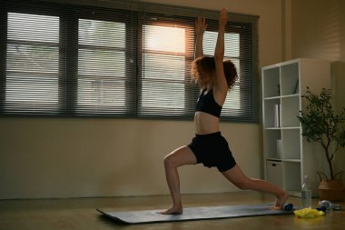 Güçlü ve dengeli olmak için parlak bir stüdyoda yoga yapan genç bir kadın..