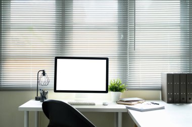 Boş bilgisayar ekranı ve düzenli kırtasiyesi olan minimalist ofis masası.