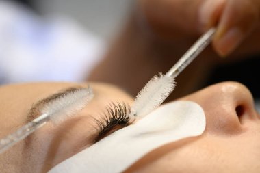 Kirpik uzantıları sırasında kirpiklerin sürtünme ve hassasiyet araçları ile şekillendirilme makro görünümü.