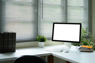 Masaüstü bilgisayarlı parlak modern çalışma alanı ve pencere perdelerinin yanındaki beyaz masadaki fare...