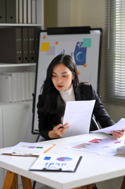 Modern bir ofis masasında baskı veri grafiklerini analiz eden odaklanmış bir iş kadını..