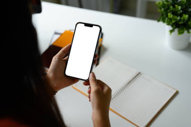 Modern bir masada boş beyaz ekranlı akıllı telefon kullanarak ellerinizi kapatın..