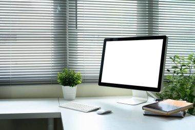 Masaüstü monitörü, kablosuz klavye ve fare, ve beyaz masadaki dizüstü bilgisayarlar.