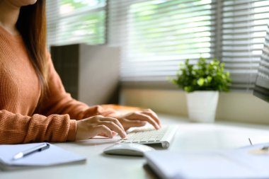 Parlak bir ofis masasında, kablosuz klavyeyle daktilo eden kadını kapat..