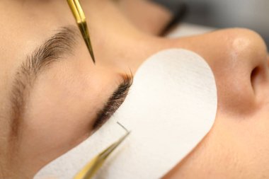 Güzellik uzmanının güzellik tedavisi sırasında cımbızla kirpik eklemesini kapat..