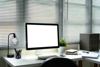 Bitkilerle çevrili boş monitör ekranı ve pencere perdelerinden gelen doğal ışık..