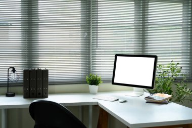 Bitkilerle çevrili boş monitör ekranı ve pencere perdelerinden gelen doğal ışık..