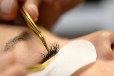 Bir istemciye kirpik eklentileri yerleştiren teknisyenin ayrıntılı görünümü.