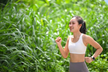 Aktif Asyalı kadın yaz güneşinde uzun çimenlerin yanında koşuyor. Refah kavramı.