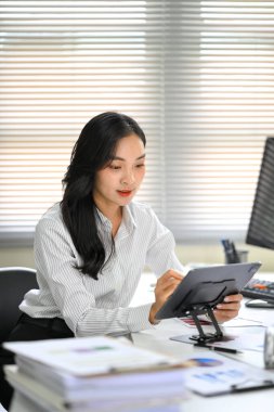 Ofis masasında dijital tablet üzerinde çalışan Asyalı iş kadını..