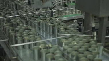 Teneke kutular endüstriyel gıda işleme tesisinde taşıyıcı bant boyunca ilerler..