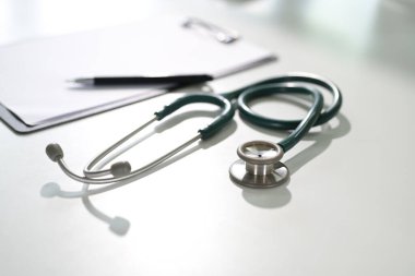 Beyaz bir masanın üzerindeki steteskop teşhis ve sağlık hizmetlerini sembolize ediyor..